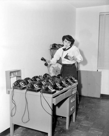 Woman trying to answer several vintage phones.
